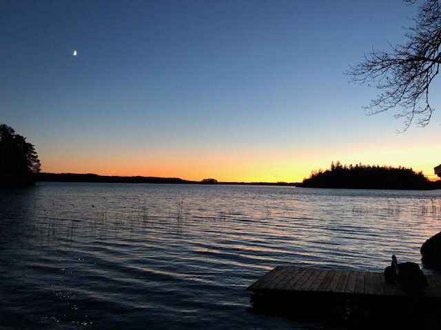 En sjö i skymningen med en brygga i förgrunden.