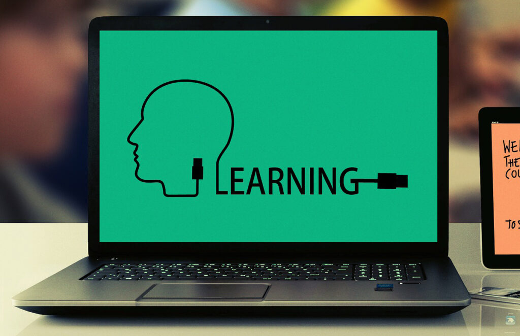 En svart dator där skärmen visar en grön bild av en illustration av ett ansikte och texten learning.