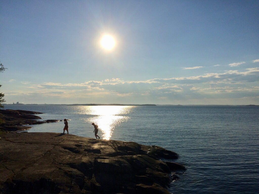 Två barn som leker på klippor vid kusten.